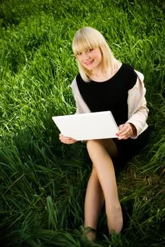 Smiling student with laptop on the grass Stock Photos