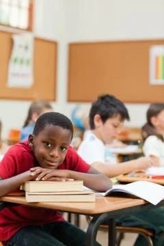 Smiling student leaning on a stack of books 스톡 사진
