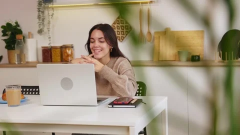 Smiling student learning online with laptop in kitchen Stock Footage 303429046