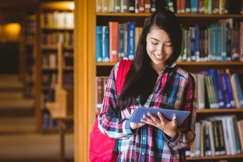 Smiling student in library using tablet 写真素材