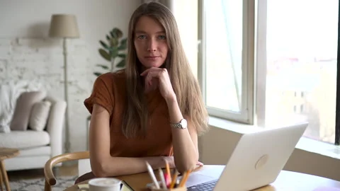 Smiling student looks at camera sitting at table with laptop Stock Footage 158980929