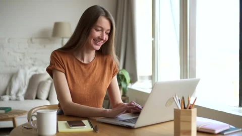 Smiling student types on laptop studying online at home Stock Footage 158367139