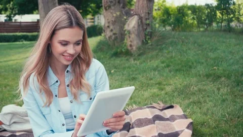 Smiling student using digital tablet on plaid in park Stock Footage 136267556