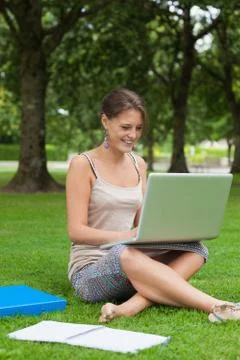Smiling student using laptop with books at the park Stock Photos