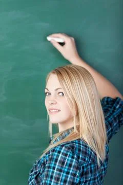 Smiling student writing on blackboard Stock Photos