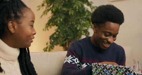 Smiling students of African appearance exchange Christmas gifts. An attractive Stock Footage 211544647