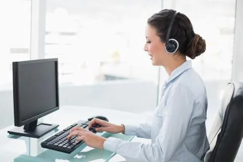 Smiling stylish brunette operator using a computer 스톡 사진