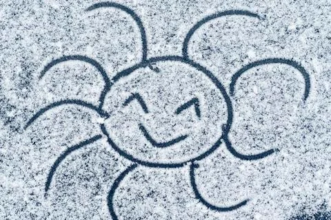 Smiling sun drawn on snow.Soft focus. Background. Close-up.Rozhitsy drawn on Stock Photos