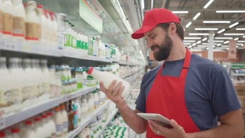 Smiling supermarket employee checking the quality of the milk Stock Footage 92326754