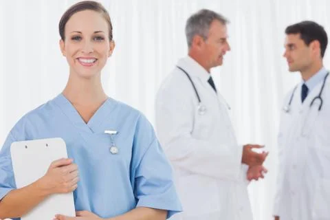 Smiling surgeon posing while doctors talking on background Stock Photos
