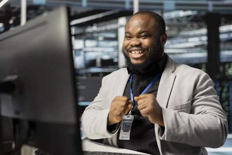 Smiling system administrator in data center pleased by stable performance Stockfoto's