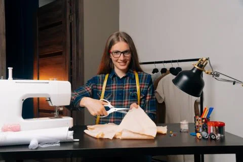 A smiling tailor look at the camera cut out a sketch of the garment. work in  Stock Photos