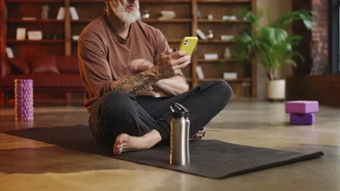 Smiling tattooed man in his 50s using a fitness tracker app after a workout Stock Footage 340902207