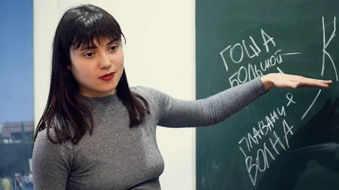 Smiling teacher explains the solution of the problem on the slate Stock Footage 94072996