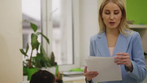 Smiling teacher giving graded test papers to primary school students Stock Footage 335684296