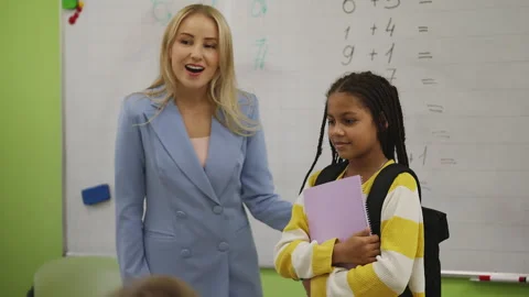 Smiling teacher introducing new African American girl student to classmates Stock Footage 335683094