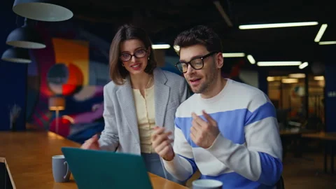 Smiling teammates video calling looking laptop webcam in creative workplace Stock Footage 335314868