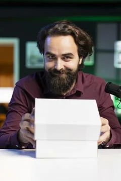 Smiling tech expert filming packaged product unboxing for technology vlog Foto stock