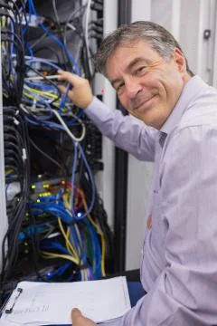 Smiling technician checking the server Stock Photos