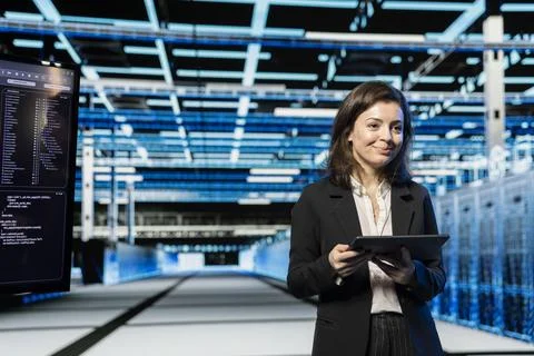 Smiling technician in data center using tablet to do digital twin scan of rigs Foto stock