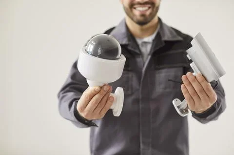 Smiling technician presenting security cameras, surveillance system, CCTV for Stock Photos
