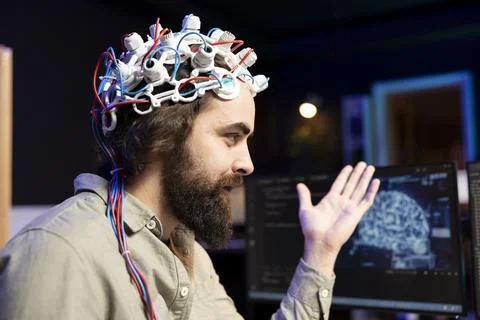 Smiling technician using EEG headset to upload consciousness into computer 스톡 사진