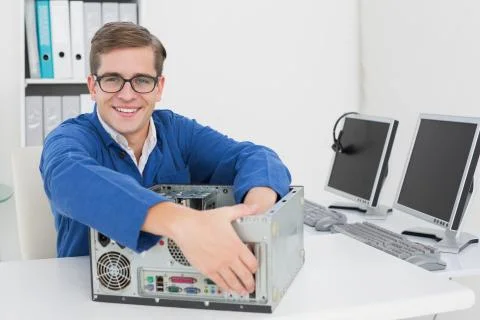 Smiling technician working on broken computer Stock Photos