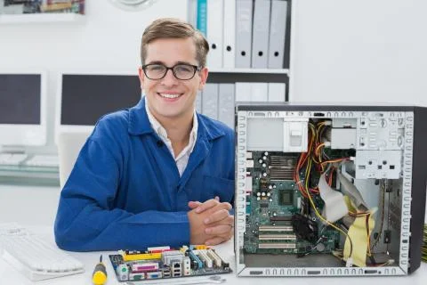 Smiling technician working on broken computer Stock Photos