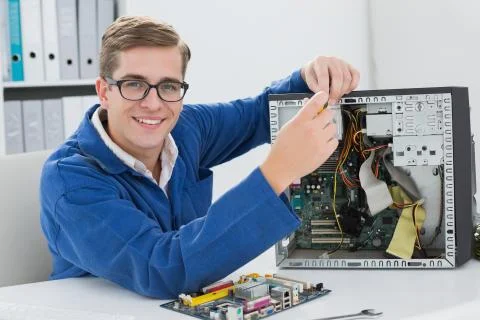 Smiling technician working on broken computer Stock Photos