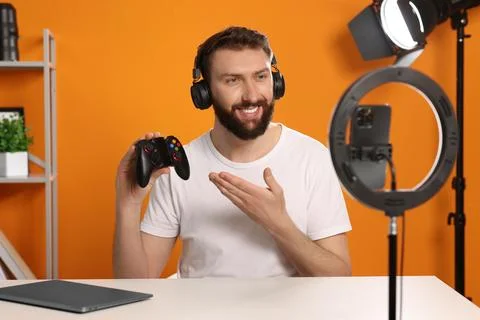 Smiling technology blogger with game controller explaining something while .. Stock Photos