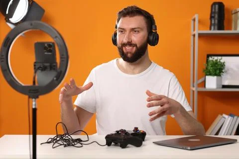 Smiling technology blogger with game controllers explaining something while.. Stock Photos
