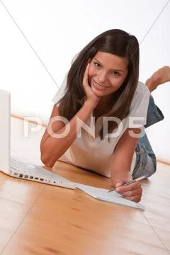 Smiling teenager lying down with laptop Stock Photos