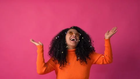 Smiling throwing confetti, Curly-haired woman on a pink background Stock Footage 231020768