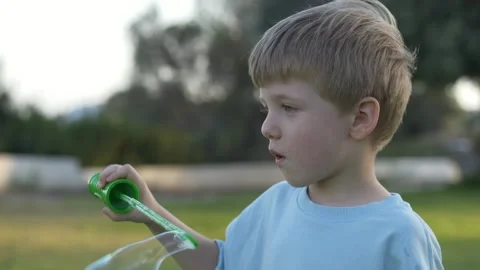 Smiling toddler plays with soap bubbles on bright day in park. Surrounded by Stock-Footage 317320276