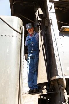 Smiling train engineer standing in vintage steam train engine Stock Photos