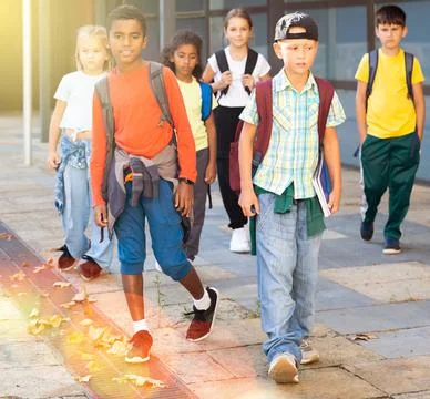 Smiling tweenagers walking outside school building on autumn day Fotos de archivo