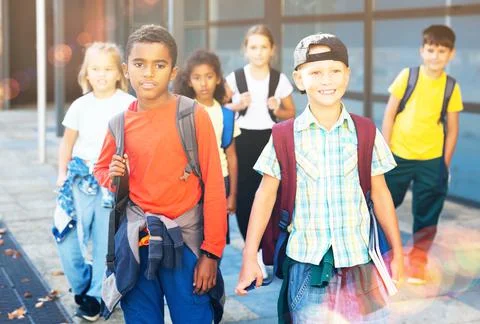 Smiling tweenagers walking outside school building on autumn day Fotos de archivo