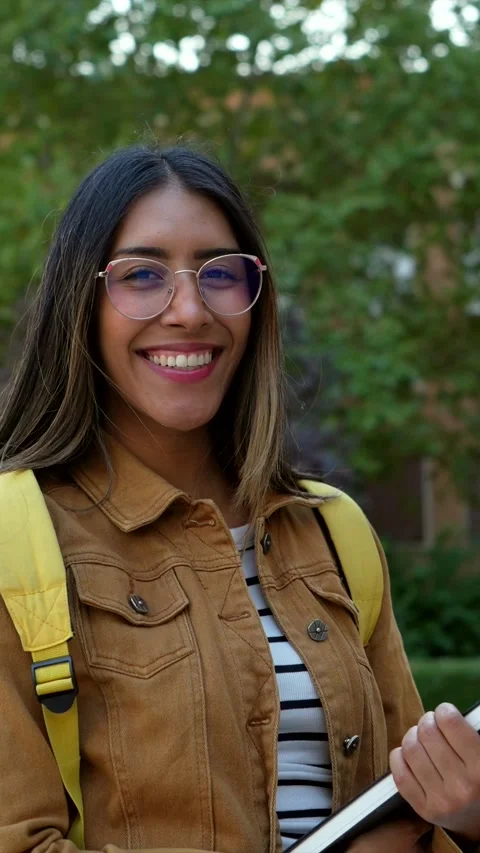 Smiling university student holding a book on campus Stock Footage 317849976