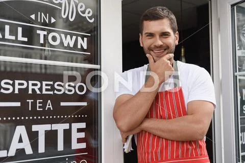 Smiling waiter standing in entrance of coffee shop Stock Photos