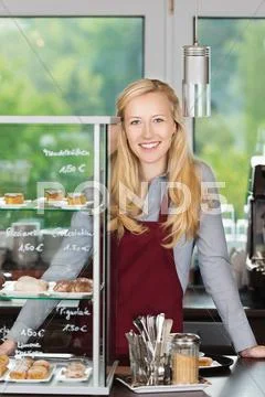 Smiling waitress leaning on coffee shop counter Stock Photos