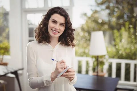 Smiling waitress writing on note pad in restaurant Photos
