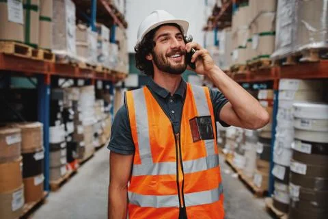 Smiling warehouse manager in conversation on mobile phone wearing white helmet Stock Photos