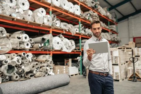 Smiling warehouse manager using a digital tablet while checking stock Stock Photos