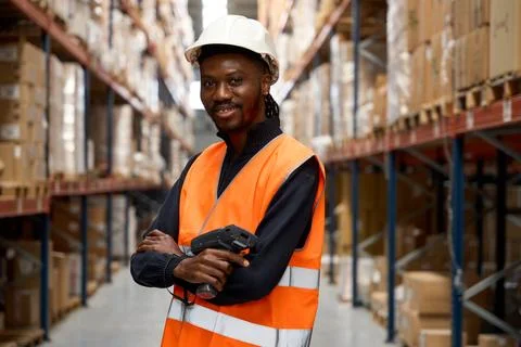 Smiling warehouse worker holding barcode scanner in logistics center Stock Photos
