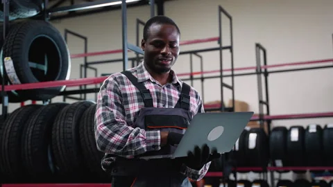 Smiling warehouse worker managing inventory with a laptop Stock Footage 301557832