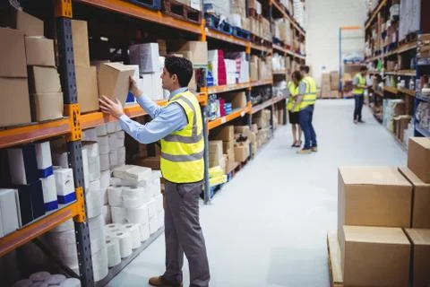 Smiling warehouse worker taking package in the shelf 스톡 사진