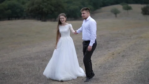 Smiling wedding couple wanders along wide brown meadow Stock Footage 122814534