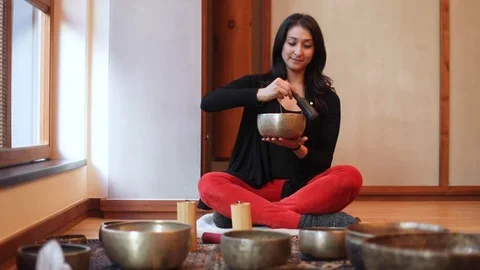 A smiling wellness practitioner uses Tibetan singing bowls for healing Stock Footage 122940358