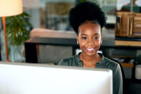 Smiling at what the future has to bring. a young businesswoman using a computer Stock Photos