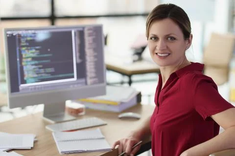 Smiling woman app developer writes code in company office Stock Photos